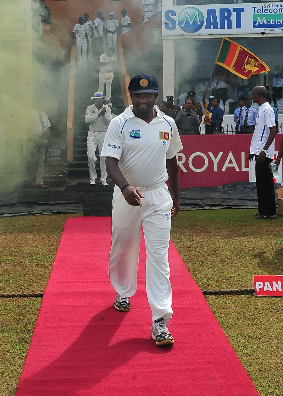 Muttiah Muralitharan walks down a red  carpet into the field for his last day of Test cricket